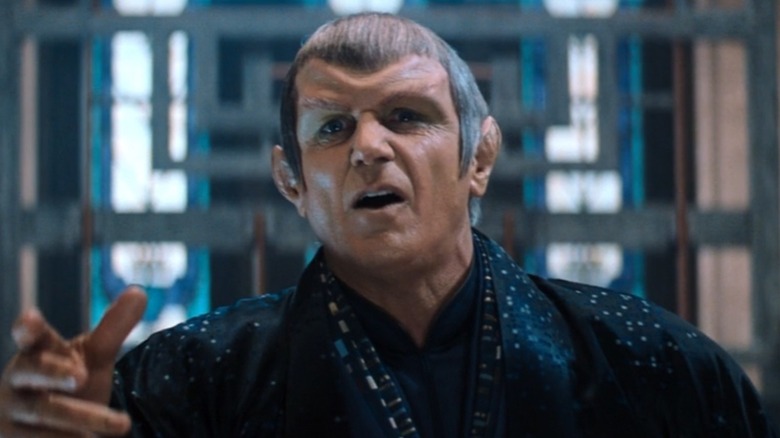 Alan Dale in alien makeup as the Romulan Praetor Hiren, his hand up in anguish, in Star Trek: Nemesis