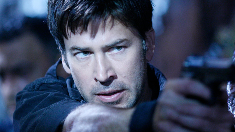 Joe Flanigan as John Sheppard, aiming a piston on Stargate Atlantis