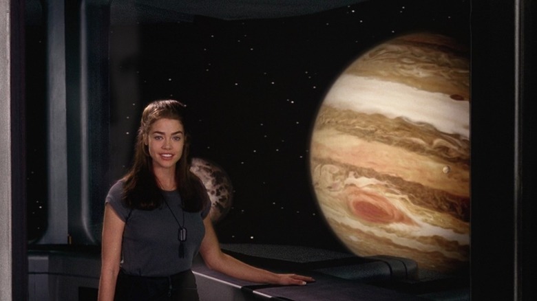 Denise Richards as Carmen Ibanez in Starship Troopers, in front of a window giving a view of Jupiter