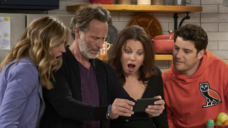 Rebecca, (Abby Elliott), Stew (Steven Weber), Debbie (Fran Drescher), and Dave (Adam Pally) look at a phone in shock in Indebted