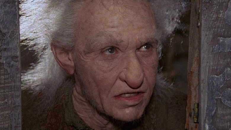 Billy Crystal as Miracle Max looking through a door hole in The Princess Bride