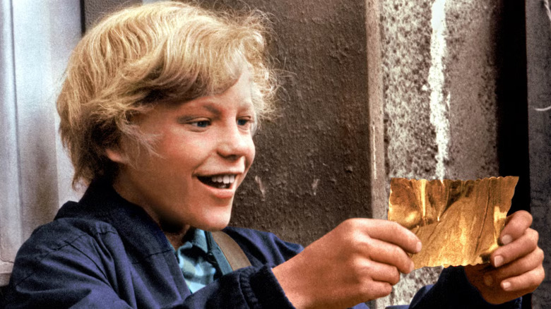 Charlie Bucket holding a golden ticket in Willy Wonka and the Chocolate Factory