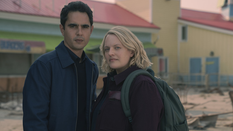 Max Minghella as Nick Blaine standing next to Elisabeth Moss as June Osborne in front of a desolate building on the set of The Handmaid's Tale