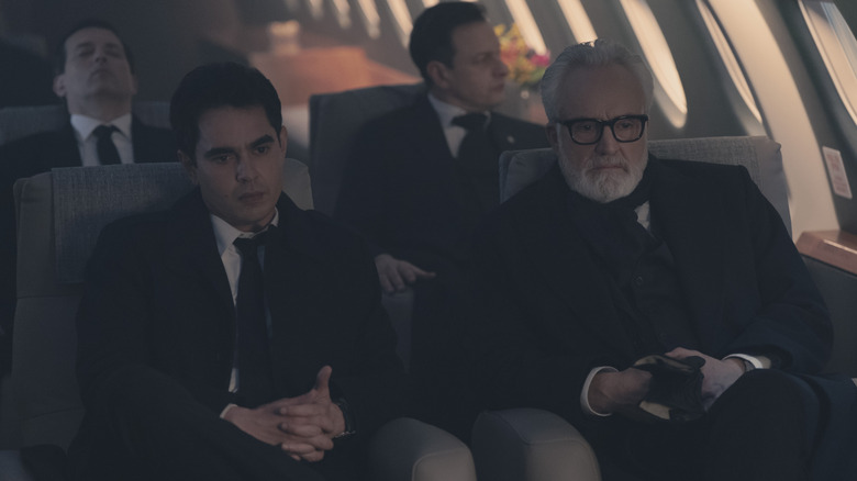 Max Minghella als Nick Blaine, zittend in een vliegtuig naast Bradley Whitford als commandant Lawrence in The Handmaid's Tale