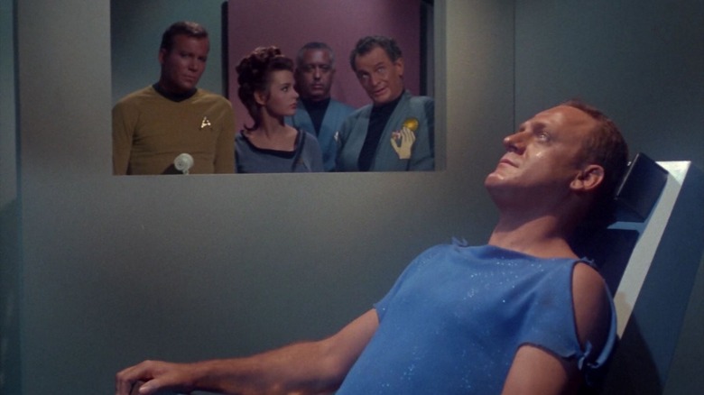 A prisoner in a chair while doctors and Captain Kirk look on on Star Trek
