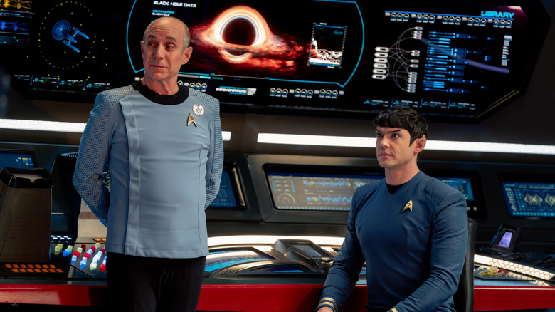 Brian Markinson as Dr. Boyce standing beside Ethan Peck as Spock by a computer panel showing a black hole in Star Trek: Strange New Worlds