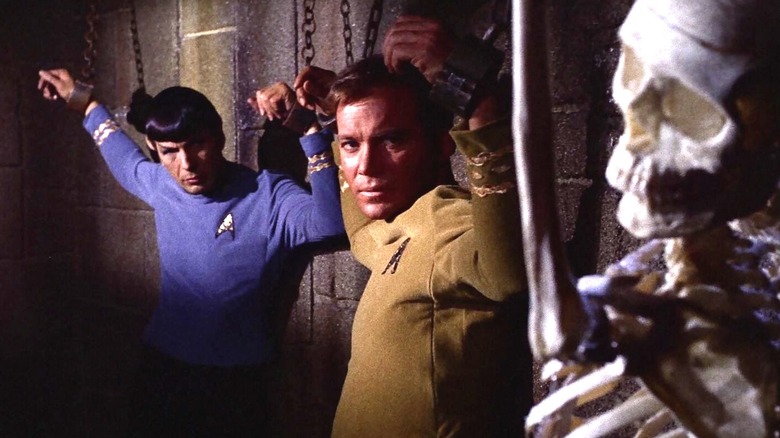 Kirk and Spock chained up in a dungeon  next to a skeleton on Star Trek