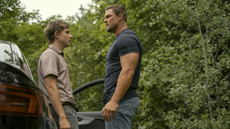 Reacher towers over a scrawny kid who's leaning up against a car