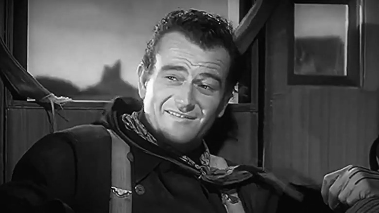 John Wayne as Henry, the Ringo Kid, smiles as he sits in the stagecoach in Stagecoach