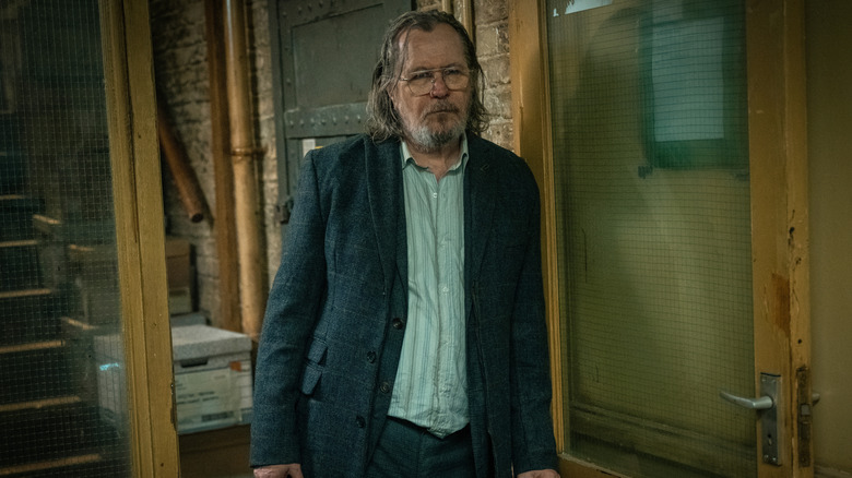Gary Oldman's Jackson Lamb leans against a door frame in Slough House in Slow Horses