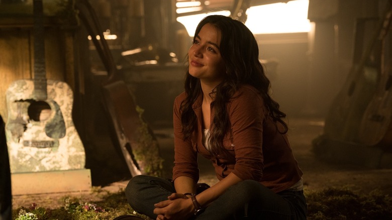 Dina listening to Ellie play guitar and smiling in The Last of Us season 2
