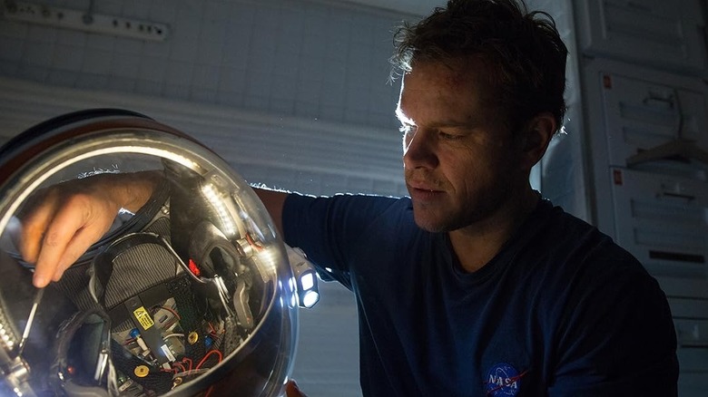Matt Damon as Mark Watney fixing his helmet in The Martian