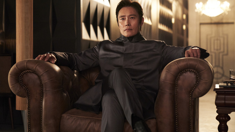 Lee Byung-hun como Front Man sentado como um vilão em uma poltrona na 2ª temporada do Squid Game
