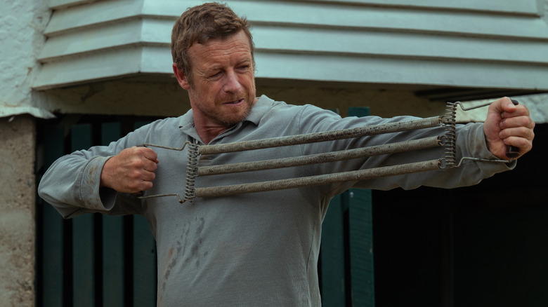 Robert Bell stretching an old-fashioned set of resistance bands in Boy Swallows Universe