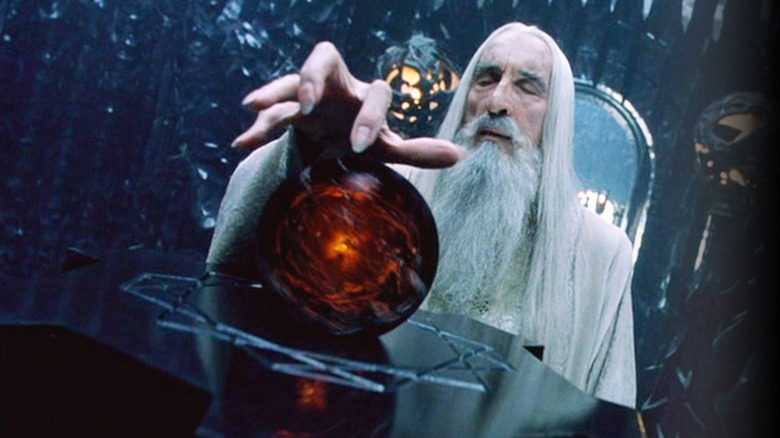 Saruman closes his eyes with arm outstretched over a palantír