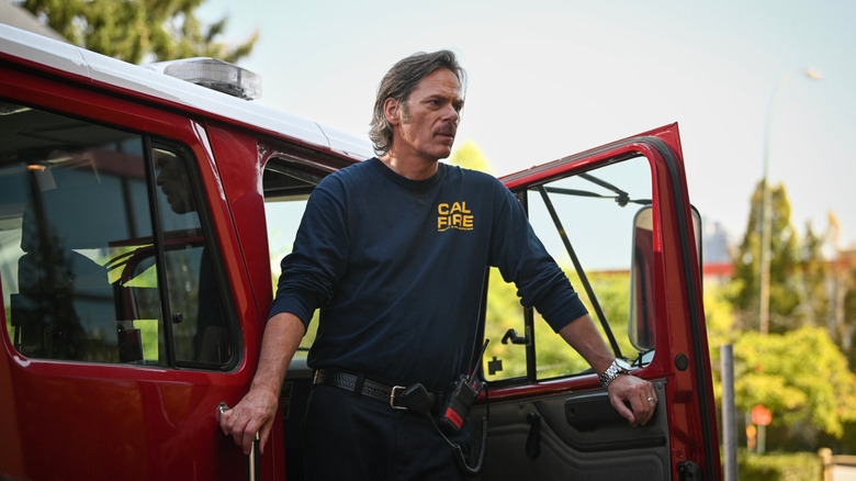 பில்லி பர்க், வின்ஸ் லியோனாக ஃபயர் கன்ட்ரியில் ஒரு தீயணைப்பு வண்டியின் கதவுக்குள் நிற்கிறார்