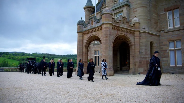 The players following Alan Cumming in front of the castle of Ardross on the traitors