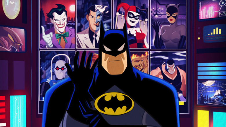 Batman standing in front of a screen showcasing his rogues