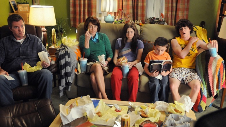 Neil Flynn as Mike Heck, Patricia Heaton as Frankie Heck, Eden Sher as Sue Heck, Atticus Shaffer as Brick Heck, and Charlie McDermott as Axl Heck sitting in the living room on The Middle