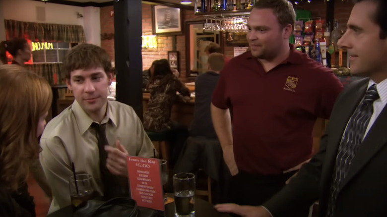 Jenna Fischer's Pam Beasley John Krasinski's Jim Halpert and Steve Carrell's Michael Scott stand inside Poor Richard's Pub in The Office