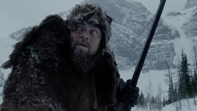 Hugh Glass holding a gun in the snow in The Revenant.