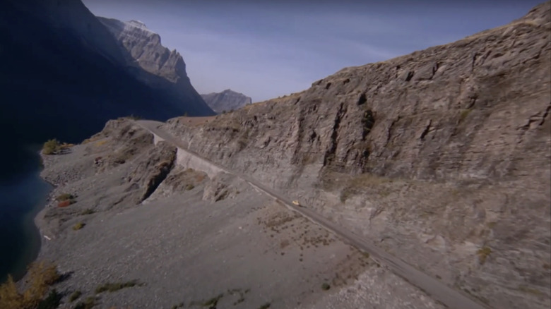 A car is seen driving along a remote mountain road from an aerial view in The Shining