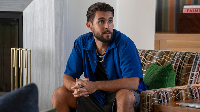 Josh Segarra as Raymond, posed on a couch on Sirens