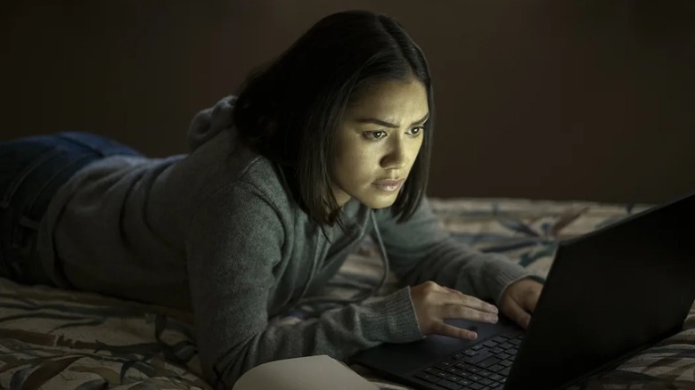 Luciane Buchanan peers into her laptop on a bed as Rose Larkin in The Night Agent