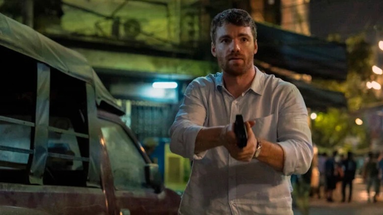 Phoenix Raei brandishes a handgun as Dale in The Night Agent