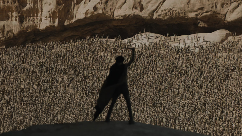Timothée Chalamet as Paul Atreides standing ominously in front of millions of followers with his knife held high in Dune: Part Two