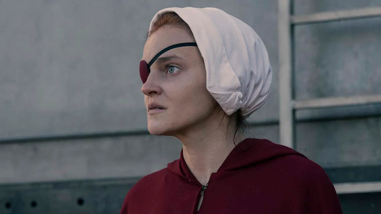 Janine wearing her eyepatch and Handmaid outfit looking frightened on The Handmaid's Tale