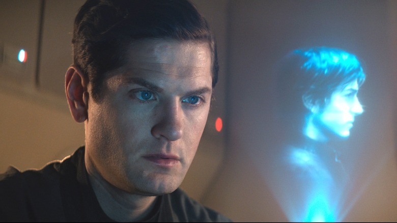 Kyle Soller as Syril Karn looking at a hologram of Diego Luna as Cassian Andor in Andor