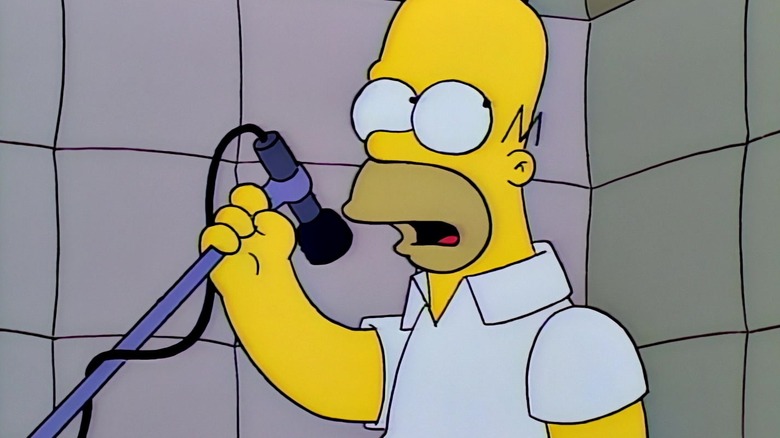 Homer Simpson in a recording booth, holding a mic on a boom. A scene from The Simpsons.