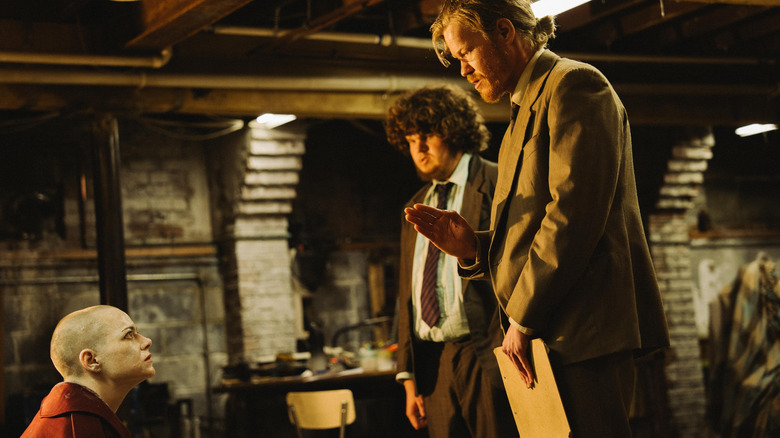 Jesse Plemons as Teddy and Aidan Delbis as Don holding Emma Stone as Michelle captive in their basement in Bugonia