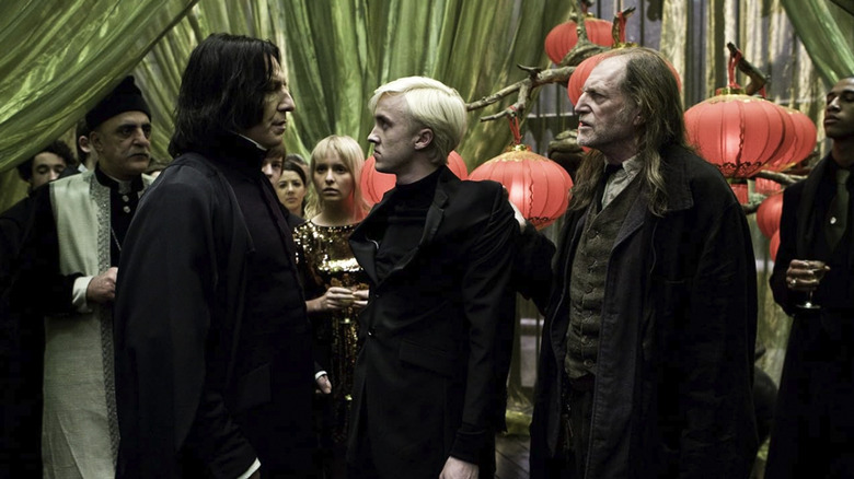 Snape, Malfoy, and Filch standing at a party in Harry Potter and the Half-Blood Prince