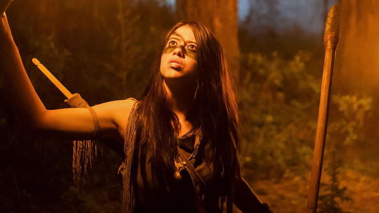 Amber Midthunder as Naru holding a flame in Prey