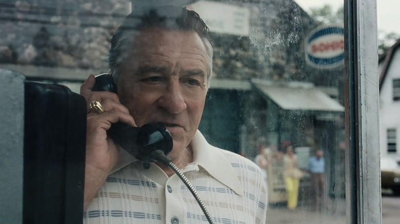 Robert De Niro as Frank Sheeran talking in a phone booth in The Irishman