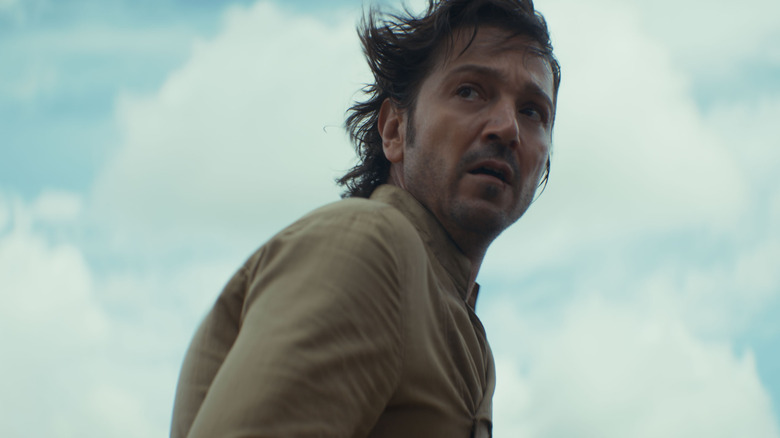 Diego Luna as Cassian Andor standing out in a field with tears in his eyes in Andor season 2