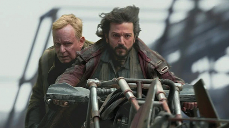 Cassian Andor (Diego Luna) and Luthen Rael (Stellan Skarsgård) riding a motorcycle in Andor season 1
