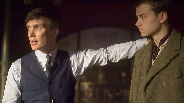 పీకీ బ్లైండర్స్‌లో డ్యూక్ షెల్బీగా కాన్రాడ్ ఖాన్ చుట్టూ తన చేతితో టామీ షెల్బీగా సిలియన్ మర్ఫీ