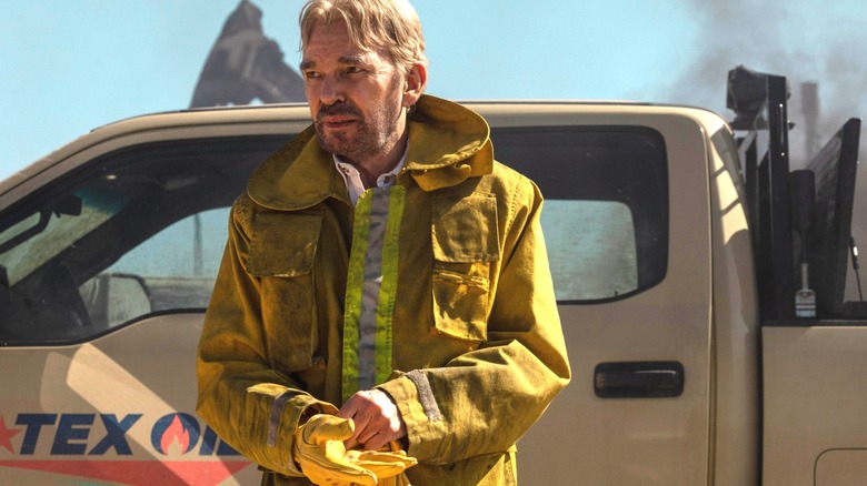 Billy Bob Thornton as Tommy Norris in fire gear leaning up against a truck in Landman