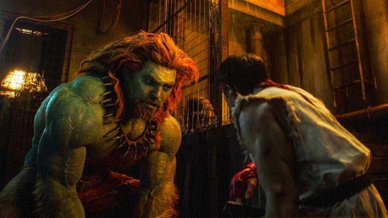 Jason Momoa as Blanka kneeling to talk to Andrew Koji as Ryu while in prison in Street Fighter (2026)