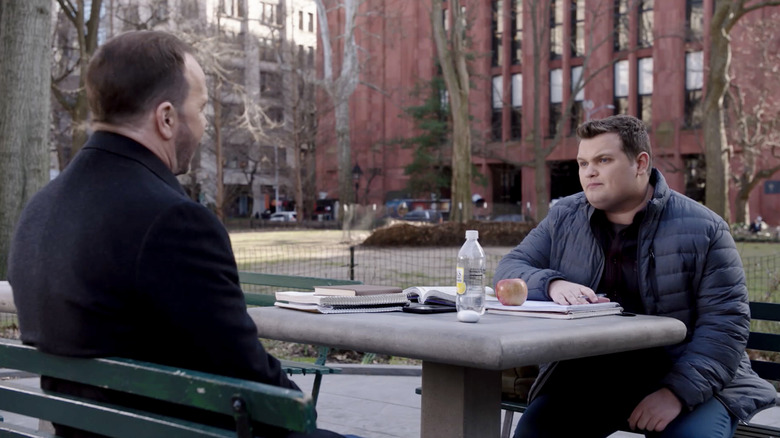 Andrew Terraciano's Sean Reagan sits opposite Donnie Wahlberg's Danny Reagan in a park in Blue Bloods