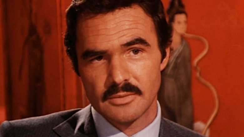 Burt Reynolds' Jack Rhodes is seen in closeup against an orange background in Rough Cut