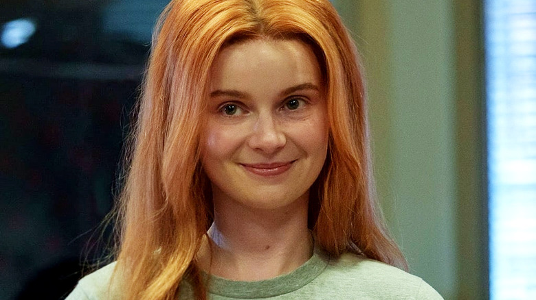 Catherine smiling and knitting in red wig in Furious