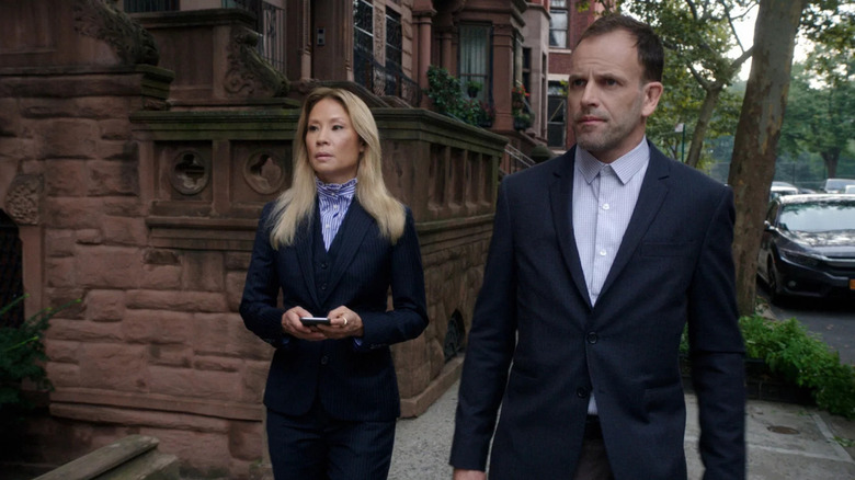 Lucy Liu in the role of Joan E. Watson and Johnny Lee Miller in the role of Sherlock Holmes, wearing suits on elementary