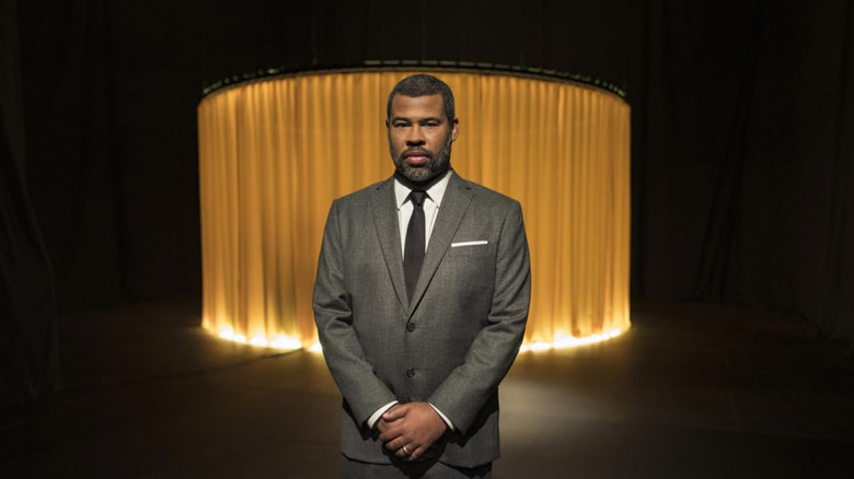Jordan Peele stands in front of a yellow curtain in The Twilight Zone