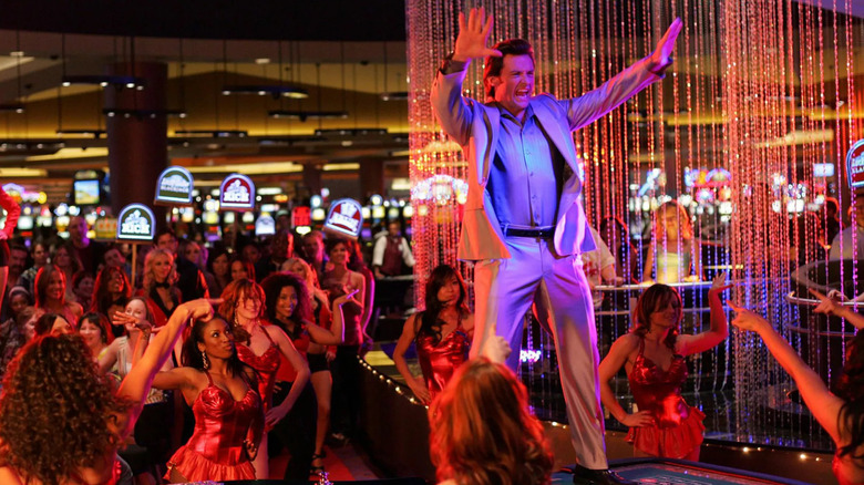 Nicky Fontana standing on a craps table, surrounded by dancers in red dresses, in Viva Laughlin
