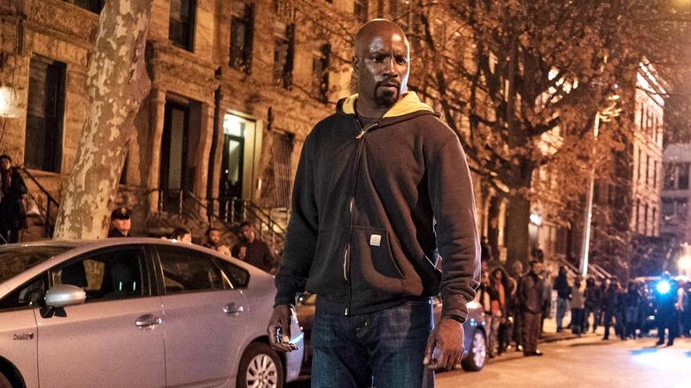 Mike Colter as Luke Cage dressed in plainclothes and standing in the middle of the street at night in an episode of Luke Cage