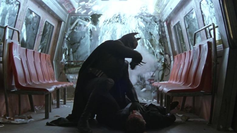 Batman Christian Bale berjongkok di atas Liam Neeson's Ra's Al Ghul di sebuah mobil Subway di Batman Begins